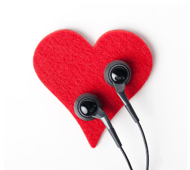 Black earbuds resting on a red felt heart shape against a white background.